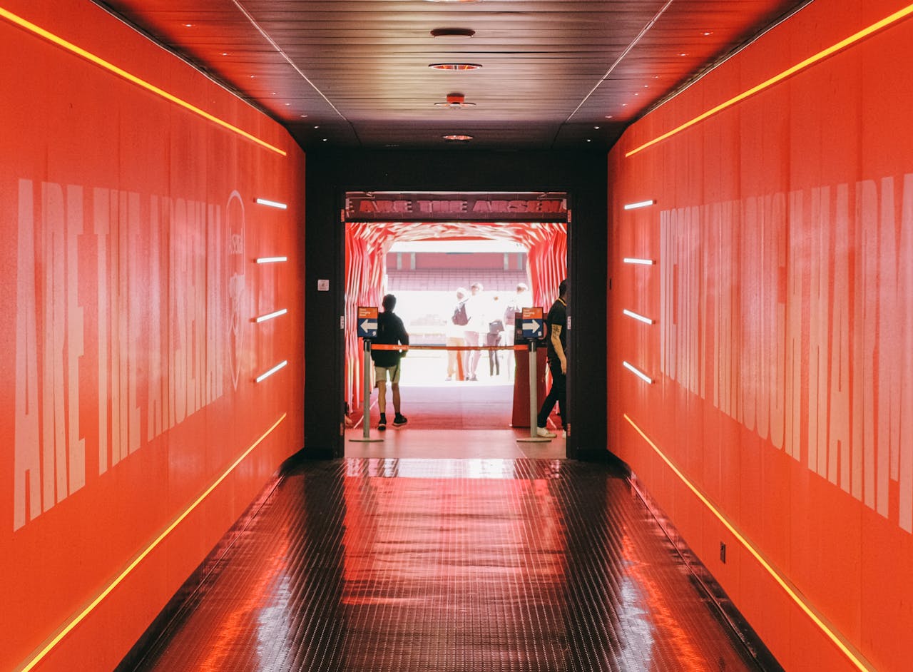 A vibrant red tunnel leading to the iconic Emirates Stadium in London, home of Arsenal FC.